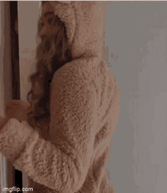 a woman wearing a teddy bear robe is standing in front of a door .