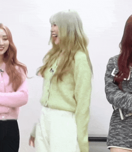 a woman in a green sweater with the letter t on it is standing next to two other women