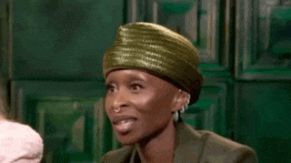 a woman wearing a green hat is making a funny face .