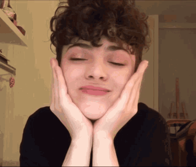a girl with curly hair is making a face with her hands