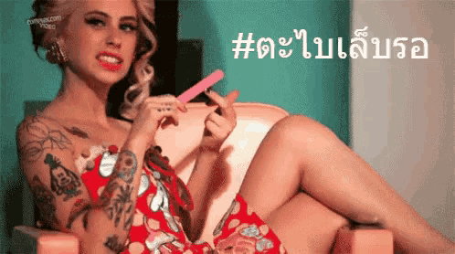 a woman in a red dress is sitting in a chair holding a nail file