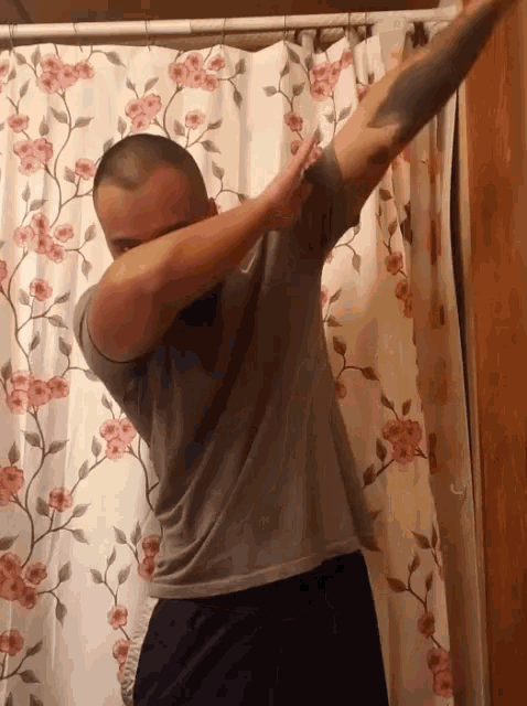 a man is doing a dab in front of a shower curtain with flowers