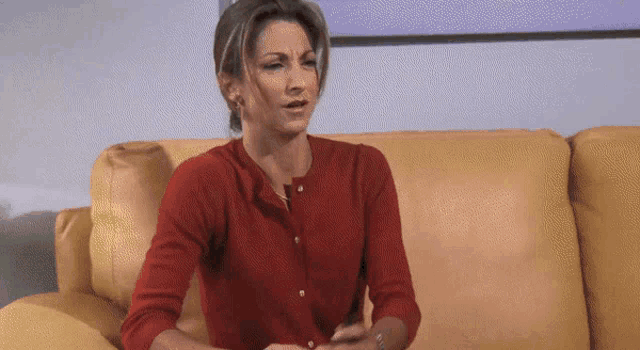 a woman in a red sweater is sitting on a couch