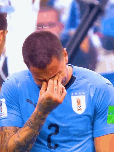 a man in a blue shirt with the number 2 on it is crying