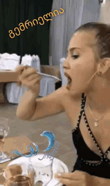 a woman in a black dress is eating something with a spoon and a sticker that says ' georgia ' on it