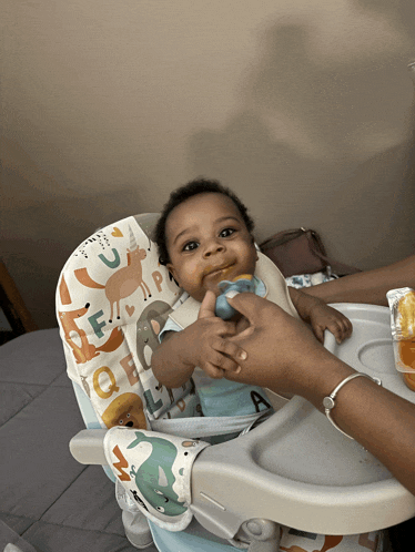 a baby is sitting in a high chair with a bib that says alphabet on it