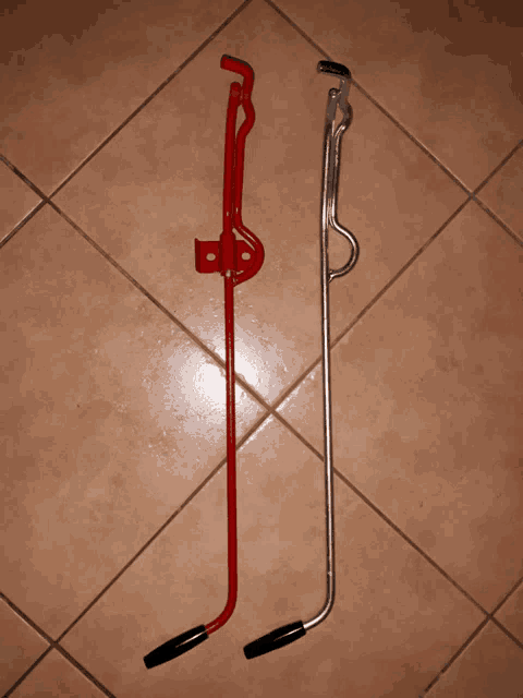 a red handle and a silver handle are on a tile floor