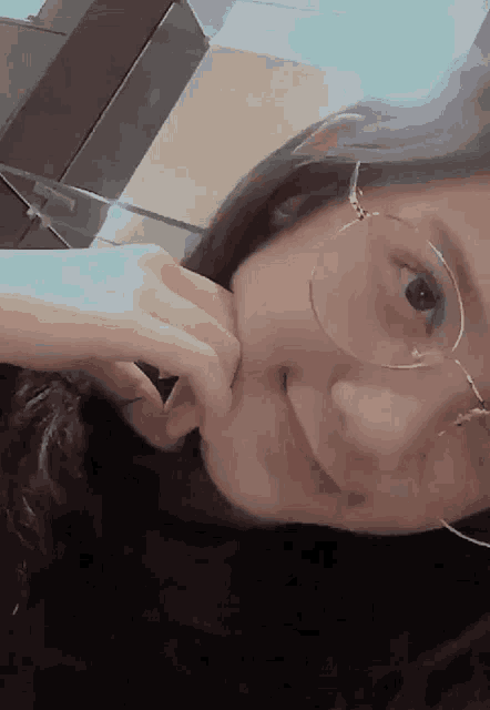 a close up of a woman wearing glasses with her hand on her face
