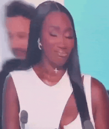 a woman in a white dress is crying on a stage .