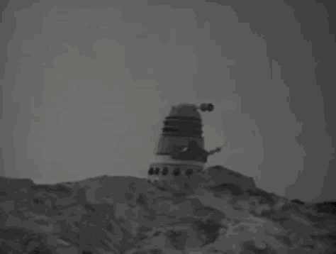 a black and white photo of a robot sitting on top of a hill with the word fuck written in white letters .