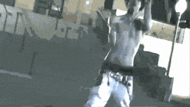 a man without a shirt is standing on a street with his arms outstretched