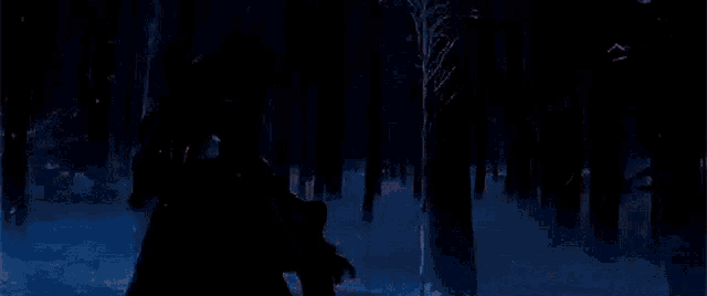 a person is standing in the middle of a snowy forest with a red light coming out of a tree .