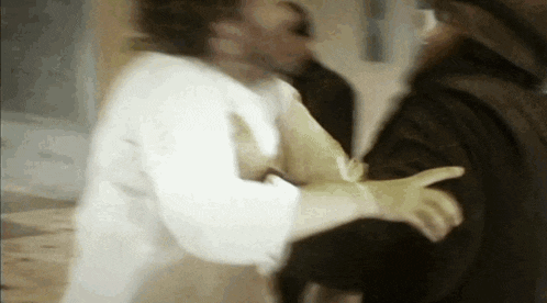 a blurry picture of a man wearing a white shirt and gloves fighting another man .