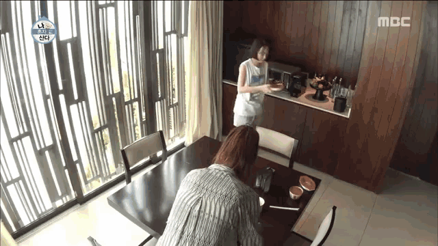 a woman is sitting at a dining table in a kitchen .