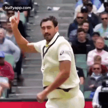 a man in a white shirt is standing in front of a crowd holding a ball .