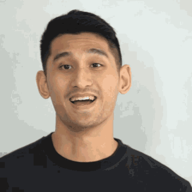 a man in a black shirt is smiling with his mouth wide open