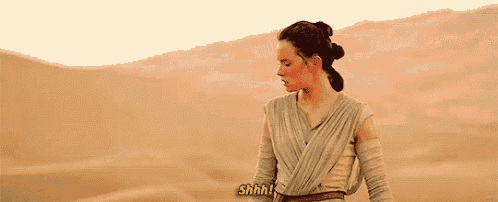 rey from star wars is standing in the middle of a desert .