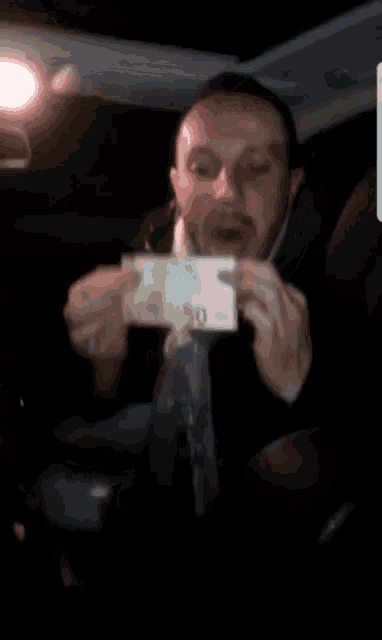 a man in a car is holding up a 20 euro bill