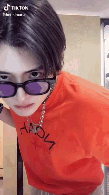 a young man wearing sunglasses and an orange shirt with the word haion written on it