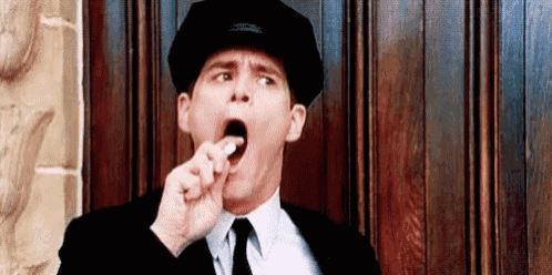 a man in a suit and tie is yawning while holding a cigarette in his mouth .