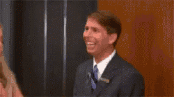 a man in a suit and tie is smiling in front of a woman .