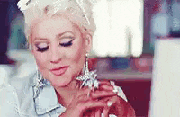 a woman wearing a denim shirt and earrings is holding a ring in her hand .