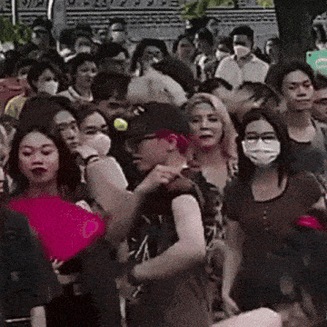 a crowd of people wearing masks and hats are standing in a park .