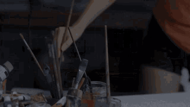 a person is holding a brush in front of a jar of paint that says ' acrylic ' on it