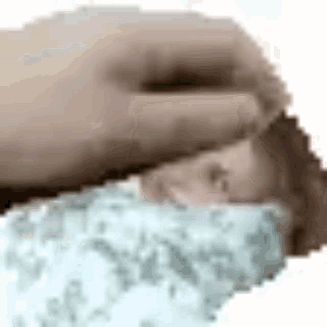 a close up of a person 's hand touching a baby 's head .