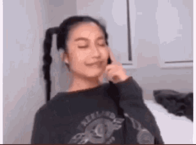 a woman is making a funny face while talking on a cell phone in a bedroom .