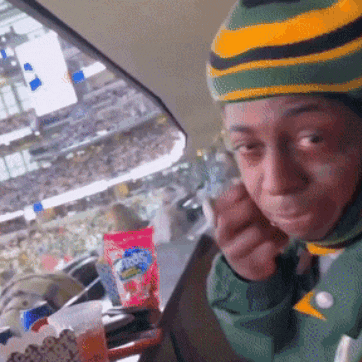 a person wearing a green and yellow striped hat is eating a snack