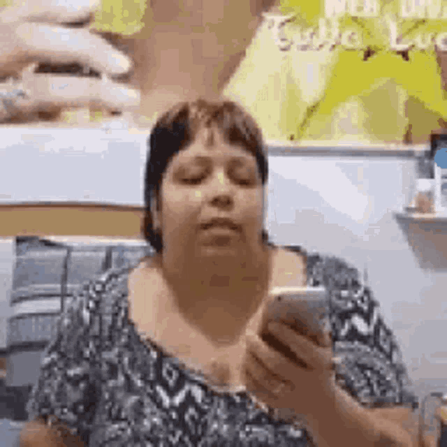 a woman is looking at her cell phone while sitting on a couch .