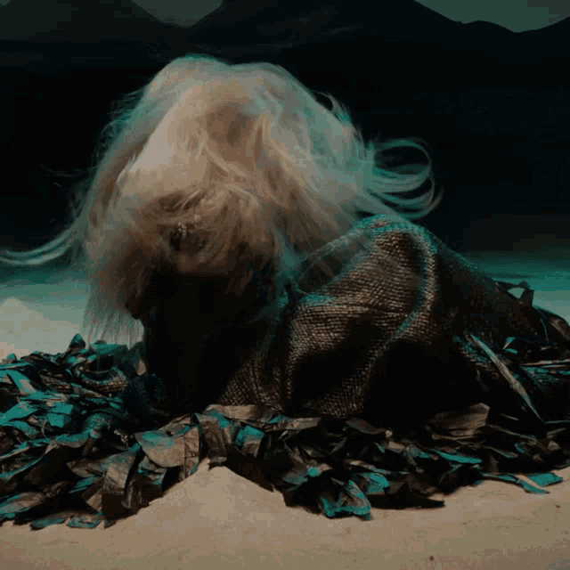 a person with long hair is laying on a pile of black and blue feathers