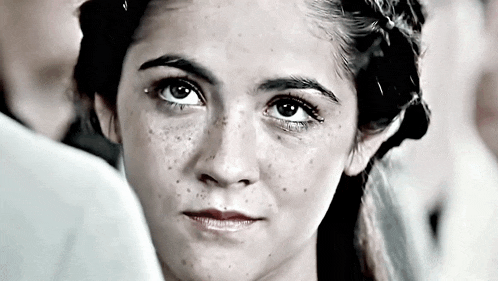 a close up of a woman 's face with freckles looking at the camera in a black and white photo .