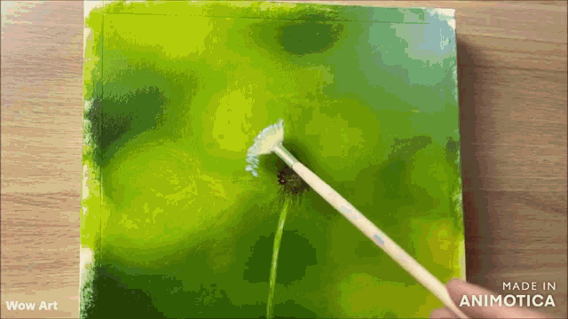 a person is painting a dandelion with a brush on a green background