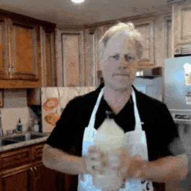 a man in an apron is holding a bottle of milk