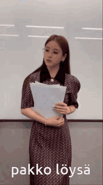 a woman in a dress is holding a piece of paper in front of a white board that says " pakko loysa " on it