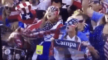 a group of people are sitting in a stadium watching a game and one of them is holding a sign that says campa