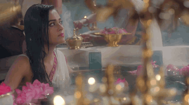 a woman in a bathtub surrounded by flowers and candles