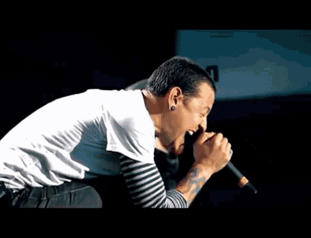 a man is singing into a microphone with a tattoo on his arm