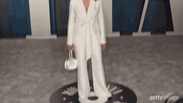 a woman in a white suit is standing in front of a vanity fair sign