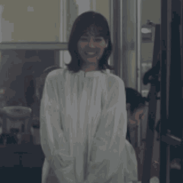 a woman in a white dress is smiling and waving .