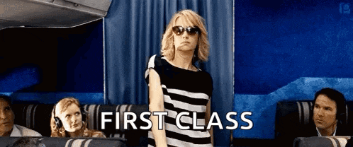 a woman wearing sunglasses is standing in the first class seat of an airplane