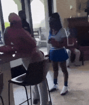 a woman in a blue skirt and white top is standing in a room