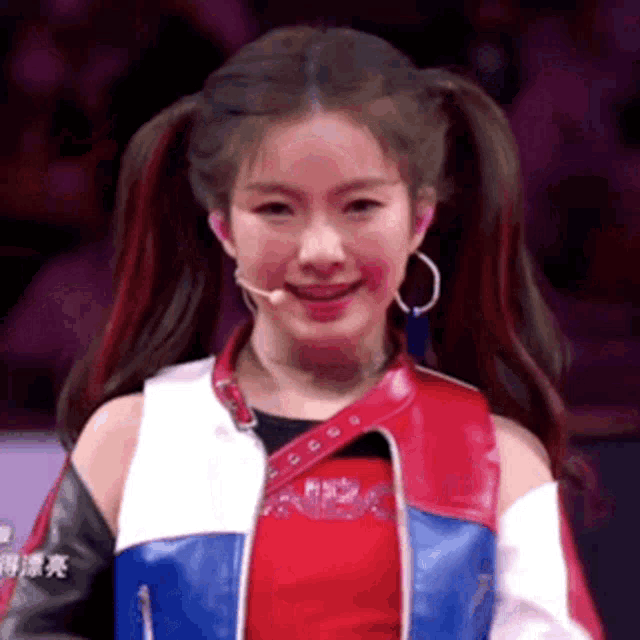 a girl with pigtails is wearing a red , white and blue jacket and earrings .