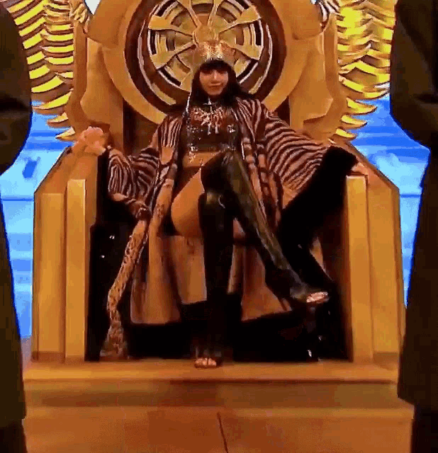 a woman is sitting on a throne wearing a crown and boots
