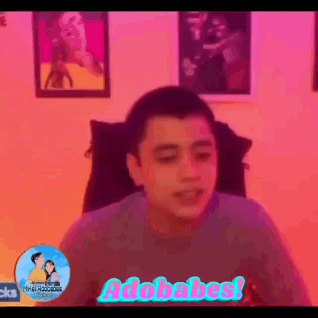 a man is sitting in a chair in front of a pink wall with a sign that says adobabes .