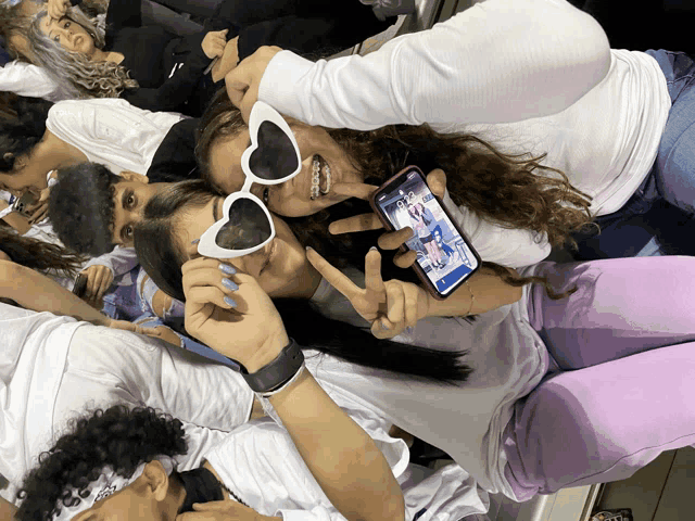 a girl wearing heart shaped sunglasses is taking a picture of herself