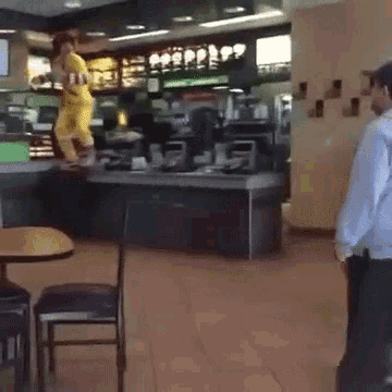 a man in a blue shirt is standing in front of a counter in a restaurant