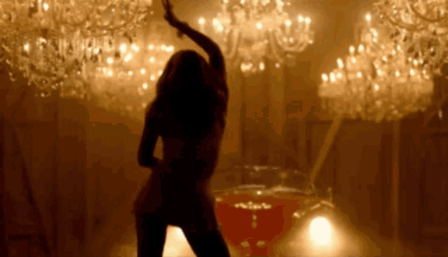 a silhouette of a woman dancing in front of chandeliers
